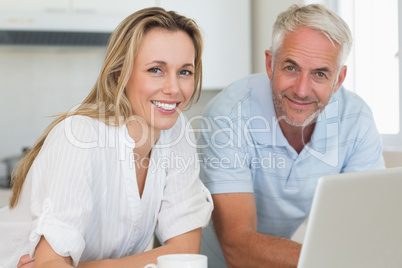 Smiling couple using laptop together at the counter Smiling couple using laptop together at the counter