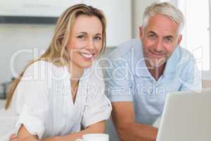 Smiling couple using laptop together at the counter