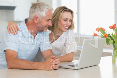 Cheerful couple using laptop together at the worktop