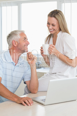 Cheerful couple using laptop together smiling at each other