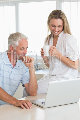 Cheerful couple using laptop together at the counter