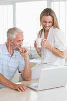 Cheerful couple using laptop together at the counter