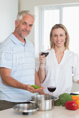 Happy couple making dinner together smiling at camera