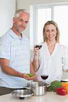 Happy couple making dinner together smiling at camera