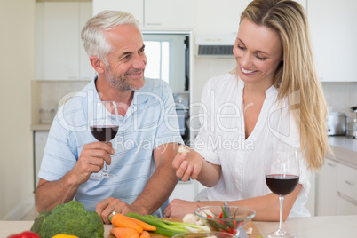 Cheerful couple making dinner together and drinking red wine