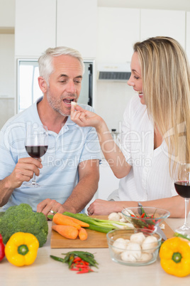 Affectionate couple preparing dinner together and drinking red w