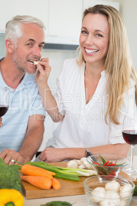 Affectionate couple preparing dinner together and drinking red w