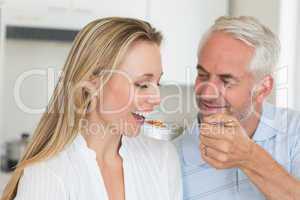 Happy man feeding his partner a spoon of vegetables
