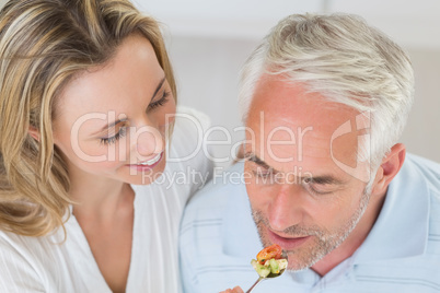 Happy woman feeding her partner a spoon of vegetables