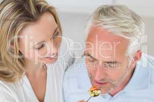 Happy woman feeding her partner a spoon of vegetables