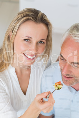 Happy woman feeding her partner a spoon of vegetables