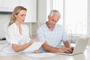 Worried couple working out their finances with laptop