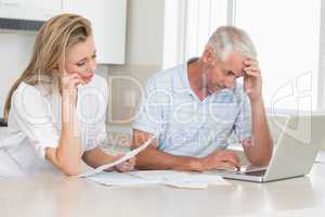 Worried couple working out their finances with laptop