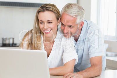 Happy couple using laptop together at the counter Happy couple using laptop together at the counter