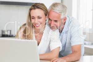 Happy couple using laptop together at the counter