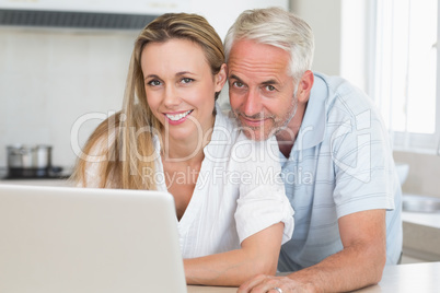 Happy couple using laptop together at the counter