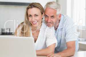 Happy couple using laptop together at the counter