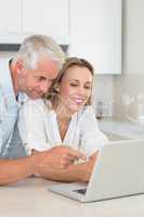 Happy couple using laptop together at the counter