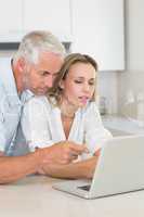 Serious couple using laptop together at the counter