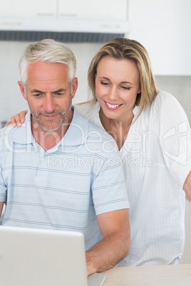 Smiling couple using laptop together at the counter