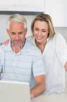 Smiling couple using laptop together at the counter