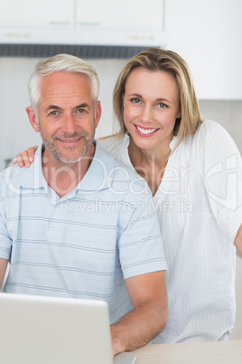 Smiling couple using laptop together at the counter Smiling couple using laptop together at the counter