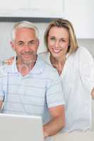 Smiling couple using laptop together at the counter