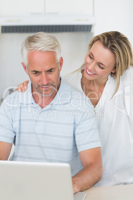 Smiling couple using laptop together at the counter