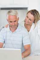 Smiling couple using laptop together at the counter