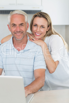 Smiling couple using laptop together at the counter