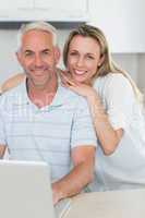 Smiling couple using laptop together at the counter