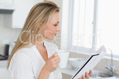 Smiling woman holding mug and newspaper