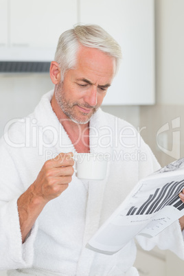 Happy man reading newspaper at breakfast in a bathrobe