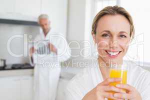 Happy woman drinking orange juice in bathrobe