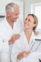 Happy couple reading newspaper together in bathrobes