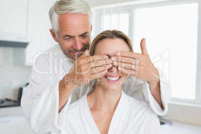 Happy man covering his partners eyes in the morning