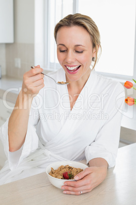 Smiling woman in bathrobe having cereal