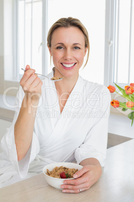 Smiling woman in bathrobe having cereal