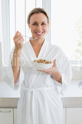 Smiling woman in bathrobe having cereal