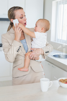 Happy businesswoman holding her baby talking on the phone