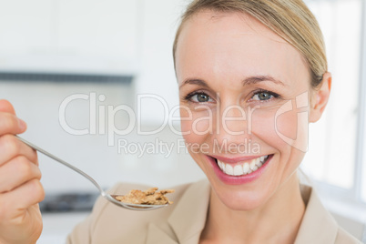 Happy businesswoman eating cereal before work in the morning