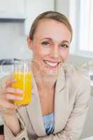 Happy businesswoman having orange juice before work in the morni