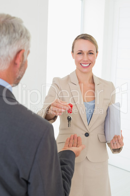 Smiling estate agent giving house key to happy customer