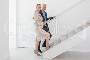 Smiling estate agent showing stairs to potential buyer