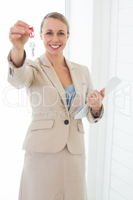 Smiling estate agent showing keys to camera