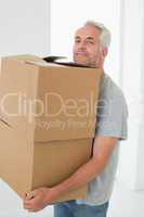 Smiling man carrying cardboard moving boxes