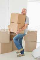 Smiling man carrying cardboard moving boxes