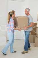 Happy couple carrying cardboard moving boxes