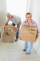 Happy couple carrying cardboard moving boxes