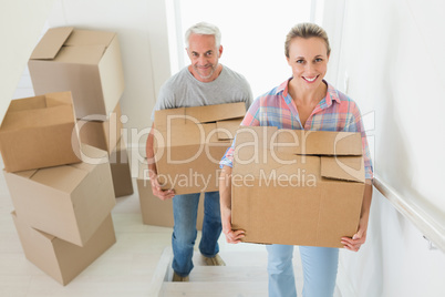 Happy couple carrying cardboard moving boxes